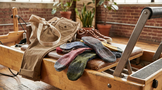 Colorful pilates grip socks arranged on a reformer carriage with silicone grip patterns visible on the soles