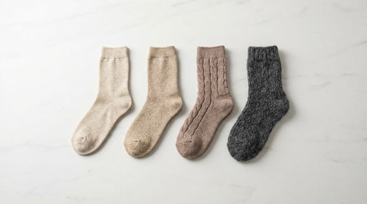 Four types of wool socks in natural earth tones showing distinct fiber textures from merino to alpaca