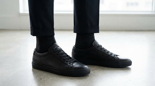 Black ankle socks paired with black leather sneakers on a clean floor minimalist style