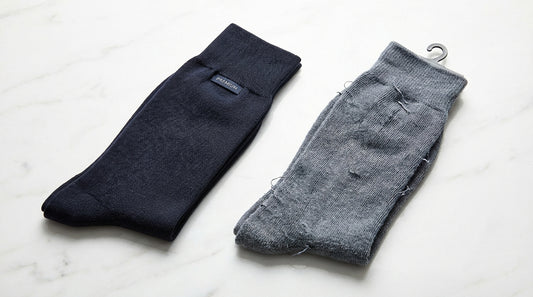 A premium dress sock and a cheap dollar store sock placed side by side on a clean white surface, showing the visible difference in knit density and construction quality