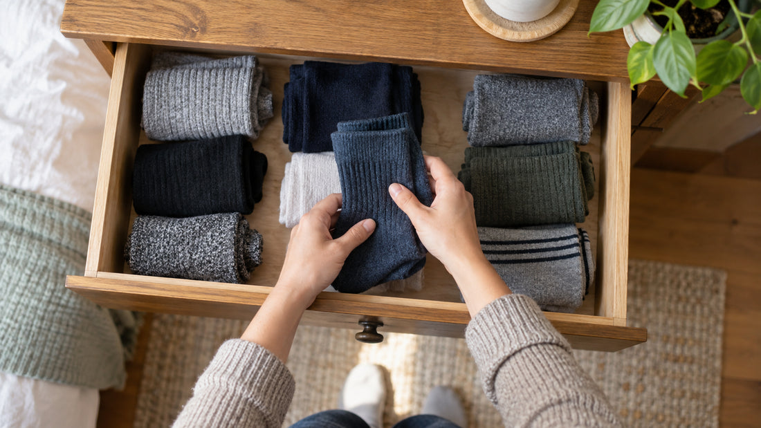 Illustrative image: a person choosing a pair of dark blue socks from a drawer of folded socks.