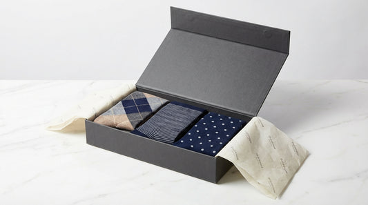 Premium sock subscription box being opened showing curated pairs in branded tissue paper