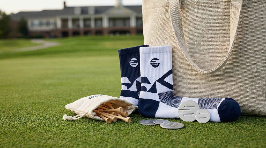 Tournament gift bag contents including custom golf socks tees and ball markers on a putting green