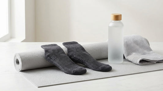 Grip socks with silicone tread on a yoga mat next to a water bottle and towel