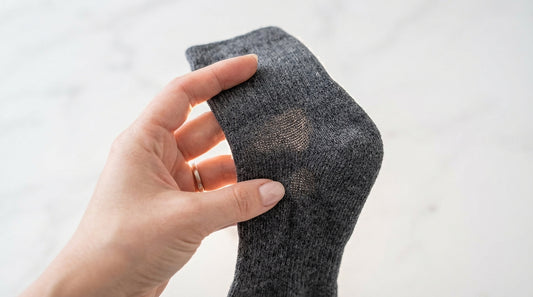 Hand holding a premium sock with light behind it showing knit density and fabric quality
