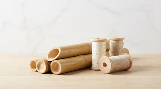 Cross-section of bamboo stalks alongside spools of bamboo viscose and lyocell yarn on a natural wood surface