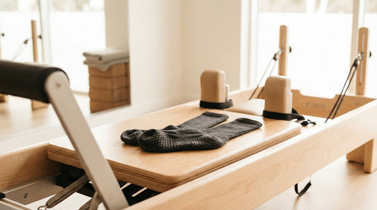 Minimalist studio grip socks on a reformer machine in a bright modern Pilates studio, clean athletic aesthetic
