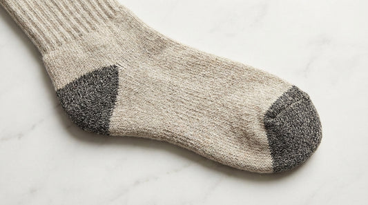 Close-up of reinforced heel and toe zones on a premium sock showing contrasting reinforcement yarn