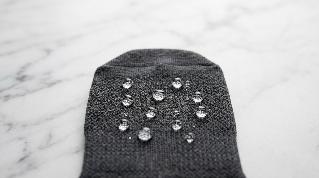 Water droplets beading on moisture-wicking sock fabric surface showing hydrophobic fiber action