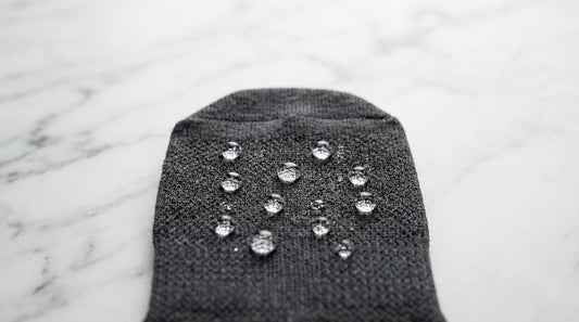 Water droplets beading on moisture-wicking sock fabric surface showing hydrophobic fiber action