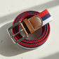 Woven belt with red, blue, and white stripes and a brown leather buckle on a light background