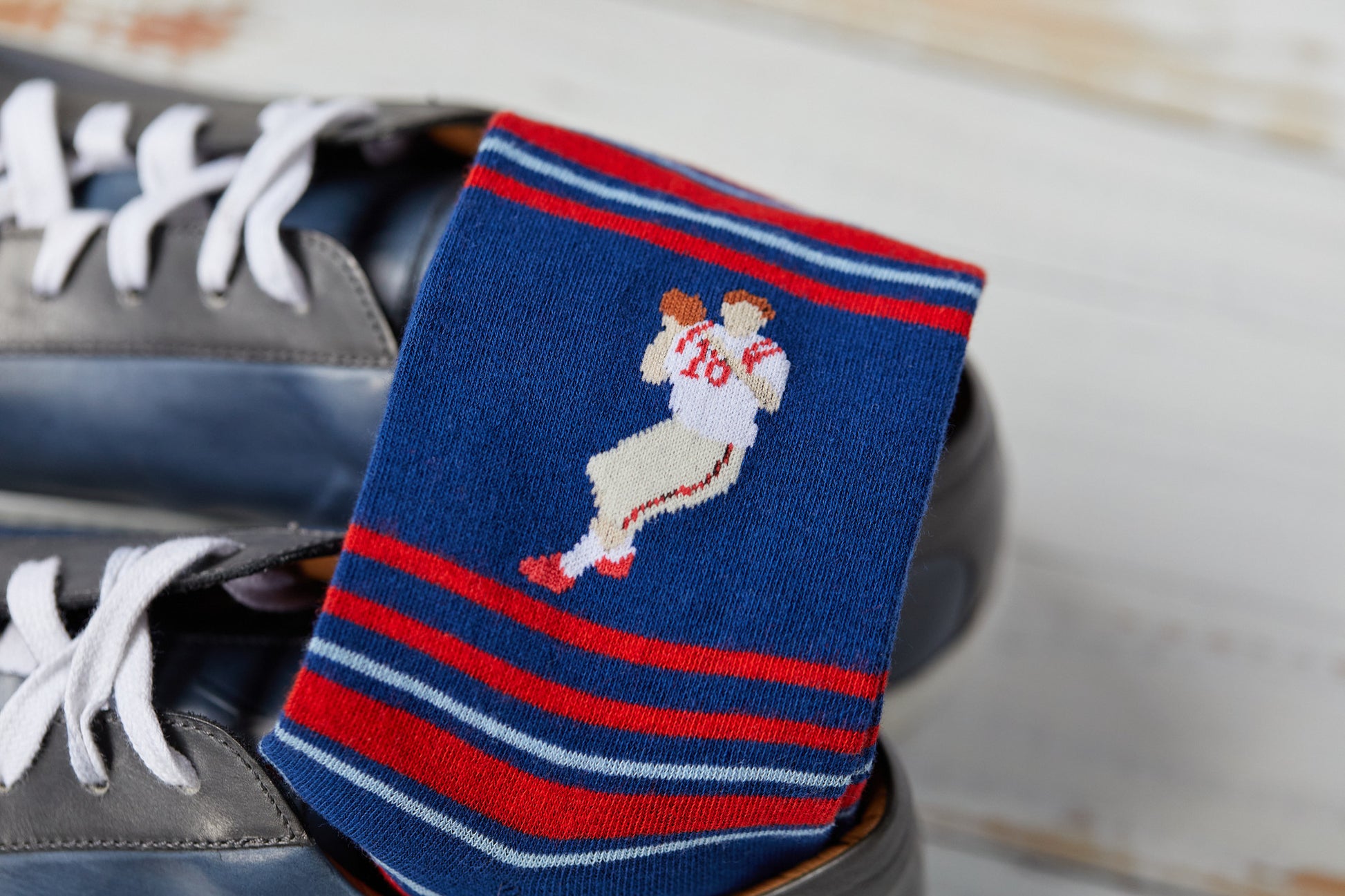 close up of the detail in the stitch on 8-bit archie red and navy stripe socks inside a grey sneaker
