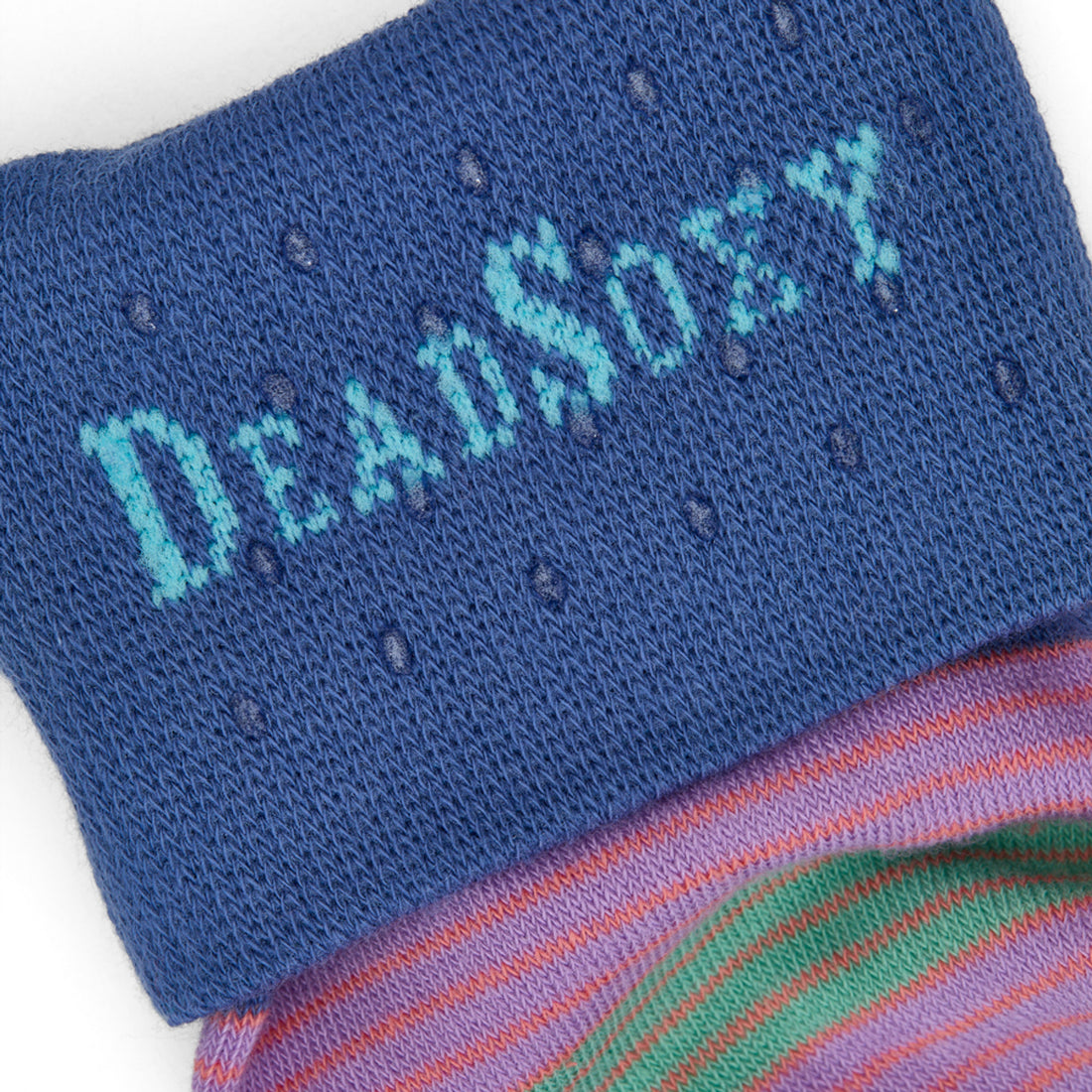 Close-up of DeadSoxy logo on cobalt TrueStay‚Ñ¢ cuff with silicone grip dots on Diego multicolor striped sock.