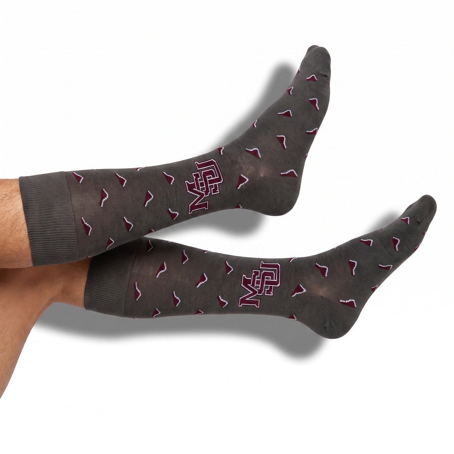 MSU Gray Cowbell Dress socks styled product shot, showing scattered maroon cowbells and the interlocking MSU logo on charcoal