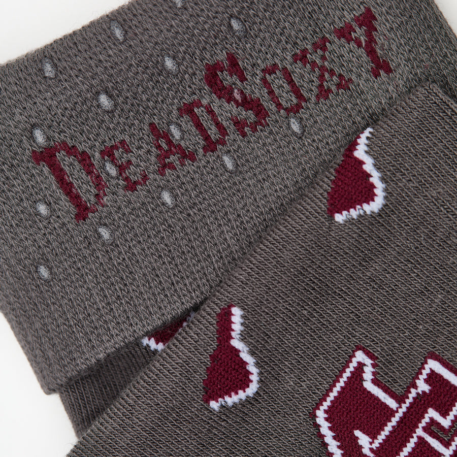 MSU Gray Cowbell Dress socks close welt and cuff detail, showing scattered maroon cowbells and the interlocking MSU logo on charcoal
