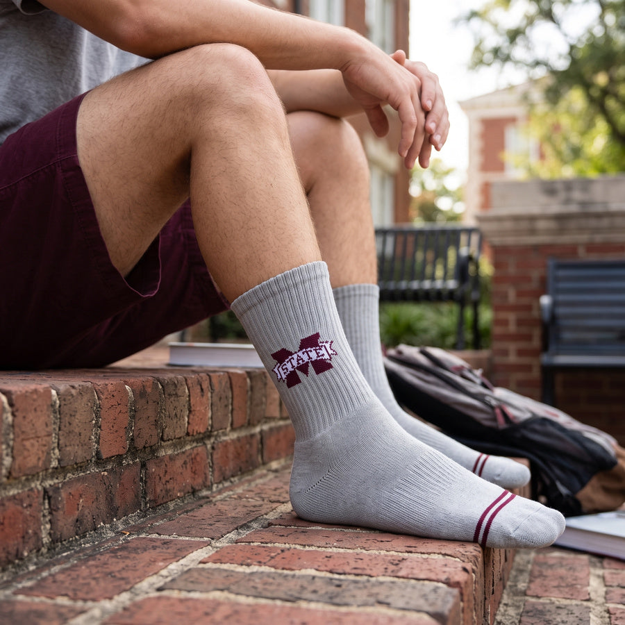 Gray M-State Logo Casual socks worn without shoes, showing the maroon M-STATE banner logo on a heather-gray crew