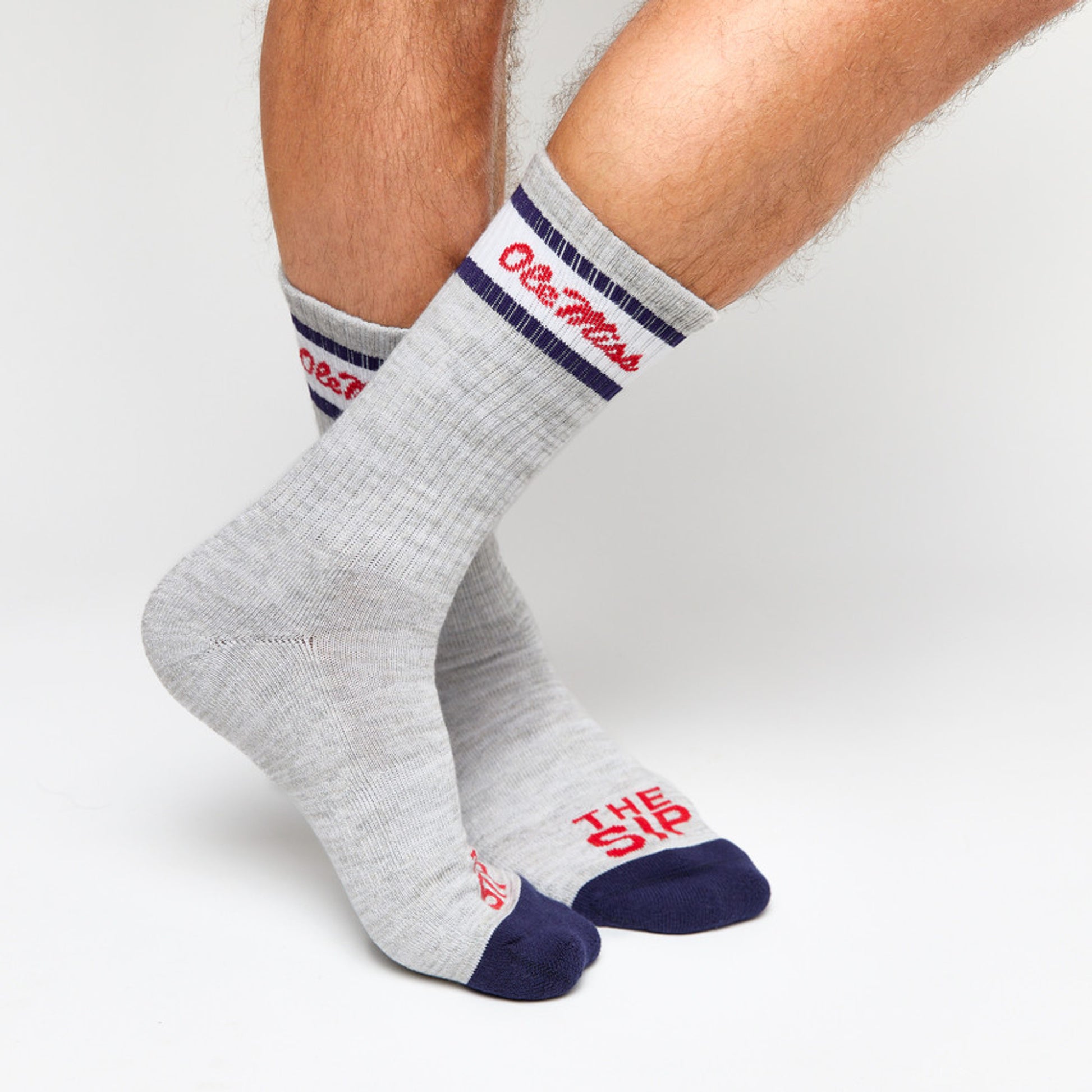 Grey casual crew socks with Ole Miss script on the leg and two retro stripes shown on legs.