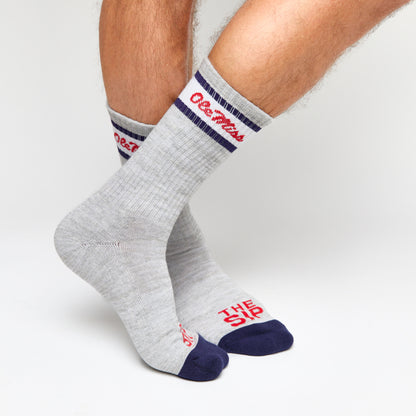 Grey casual crew socks with Ole Miss script on the leg and two retro stripes shown on legs.