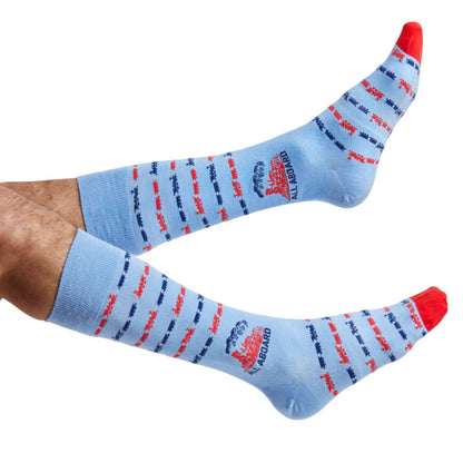 Powder Blue dress socks with trains and text saying ALL ABOARD the lane train shown on legs coming into the left side of the image