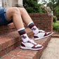 MSU Retro Stripe Casual socks worn seated on campus, showing maroon and gray banding with the interlocking MSU logo on white
