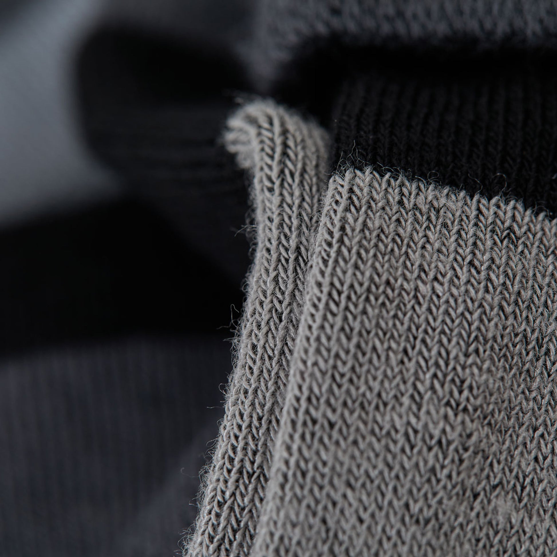 Close up macro image of yarn in monochrome dress socks showcasing a gradient of greys
