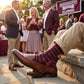 MSU Hail State Dress socks worn seated, second angle, showing repeating HAIL STATE text in white and gray on maroon