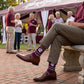 MSU Helmet Dress socks worn seated, showing the State-script football helmet and fine striping on maroon