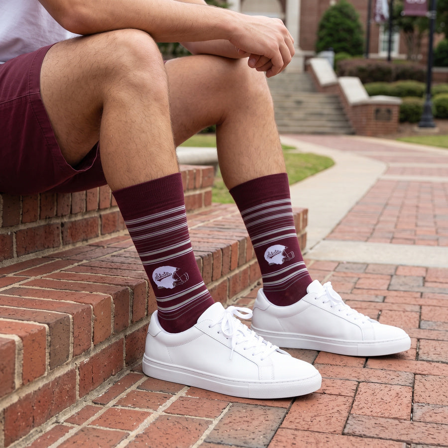 MSU Helmet Dress socks worn seated on campus, showing the State-script football helmet and fine striping on maroon