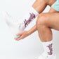 white crew socks with Howdy on the leg worn by a woman sitting in cream shoes