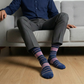 Person sitting on a couch wearing striped socks with a neutral background