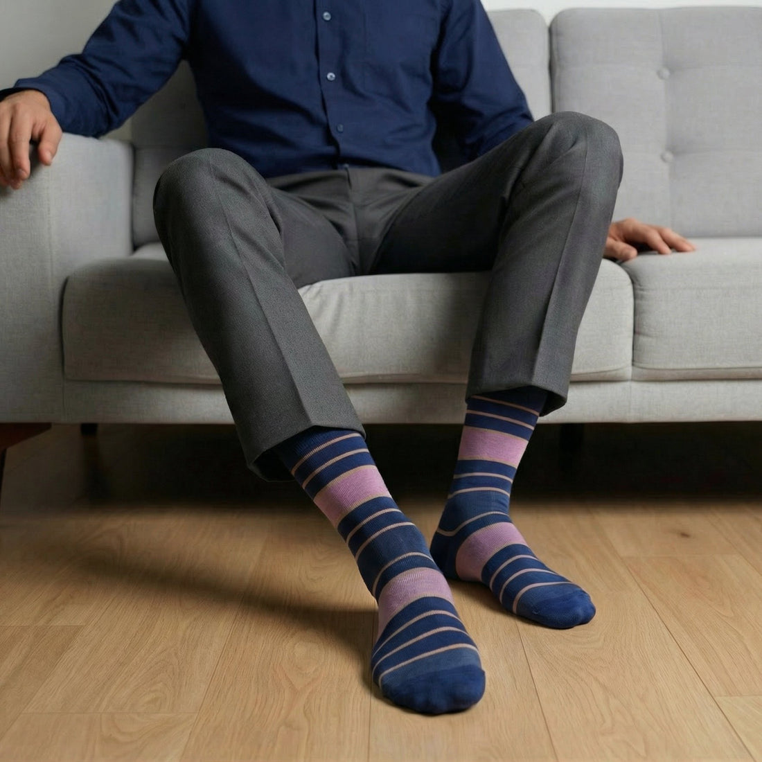 Person sitting on a couch wearing striped socks with a neutral background