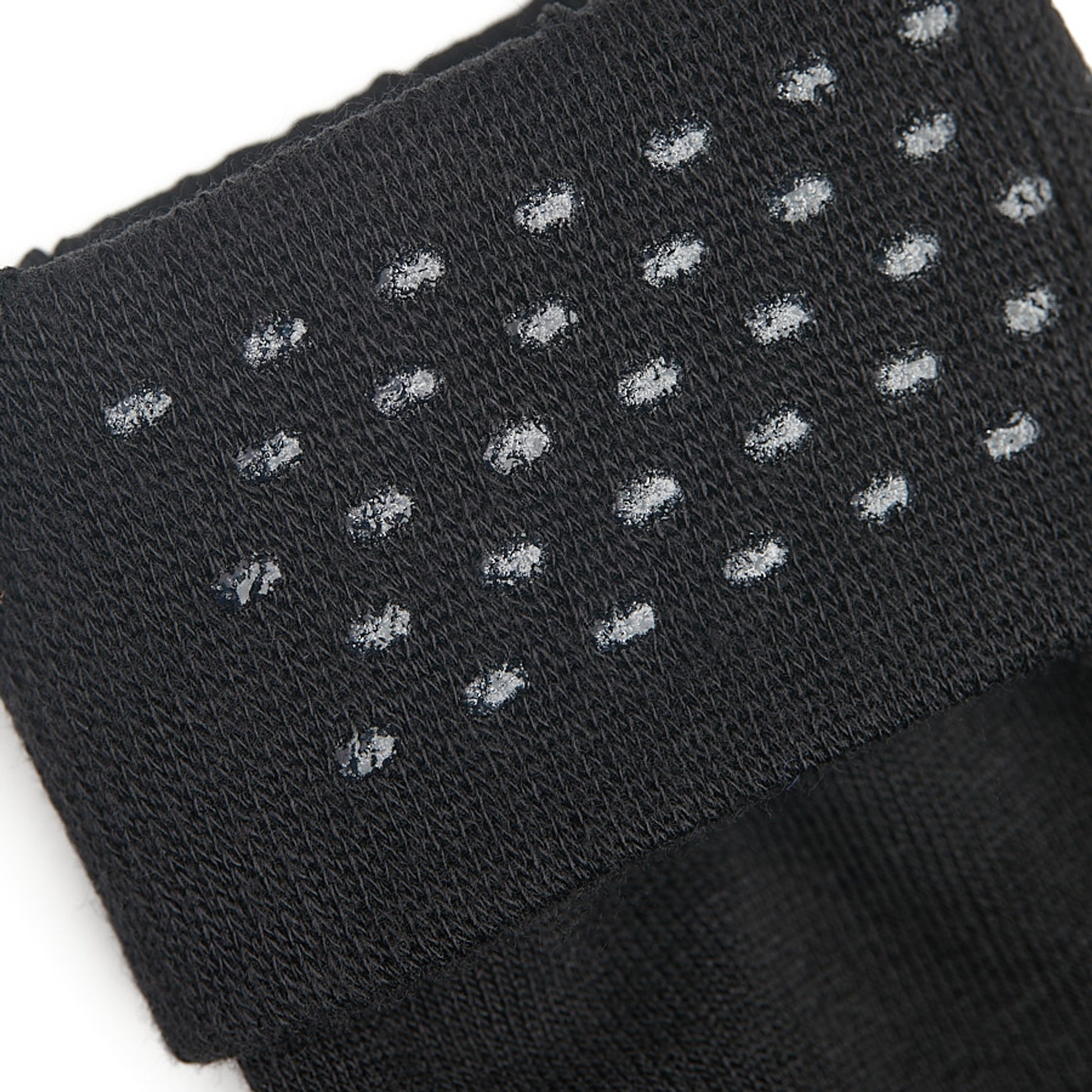 Close up shot of black sock welt featuring clear silicone dots