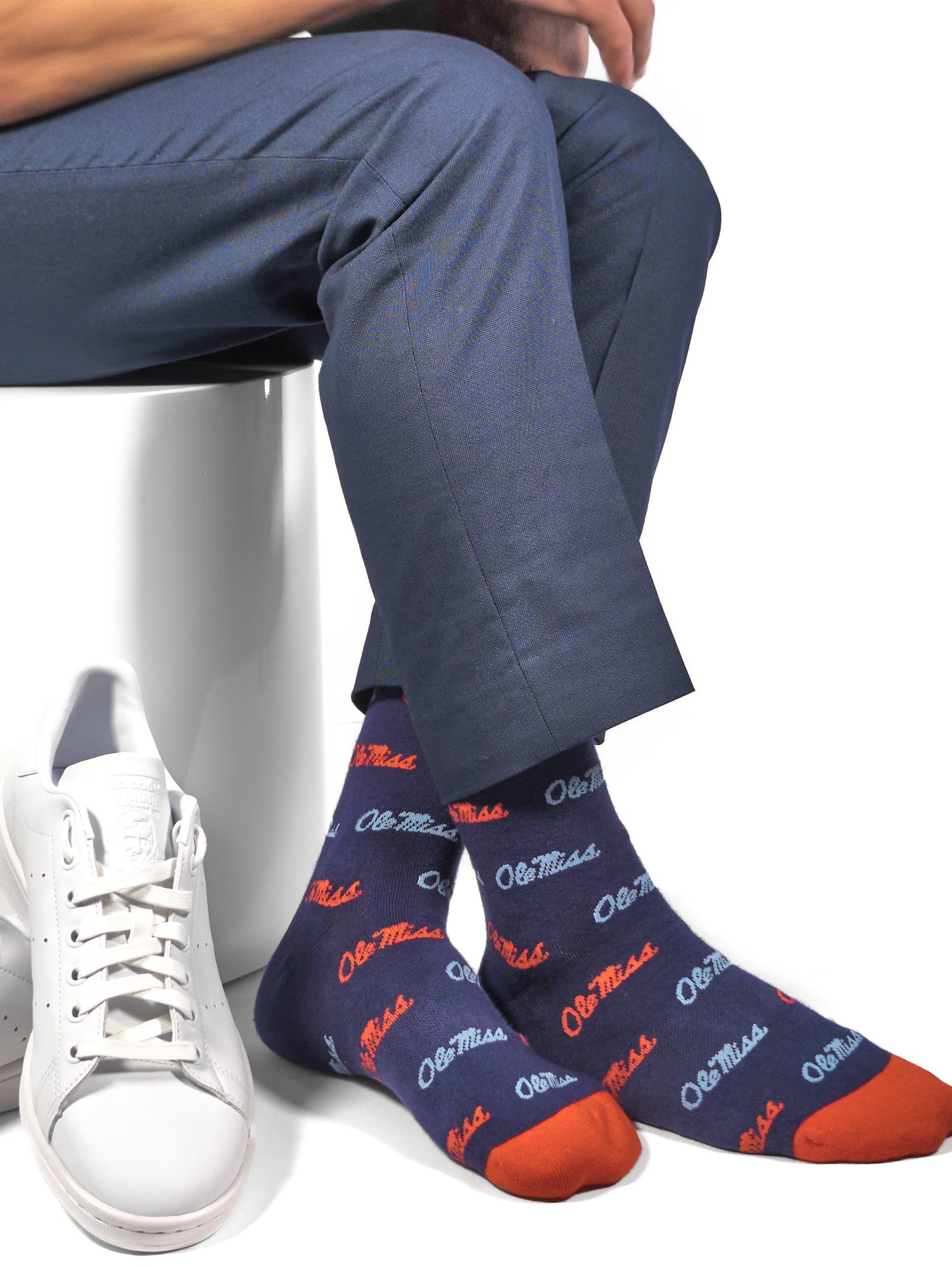 Licensed navy blue dress socks with the Ole Miss script logo in red and powder blue blue in repeating pattern shown close up.