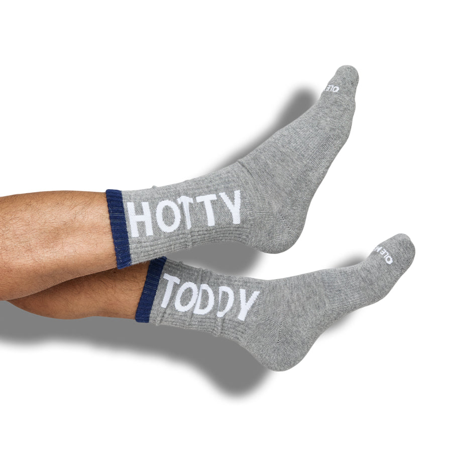 Gray casual crew socks with 'HOTTY TODDY' text worn by a person on a white background