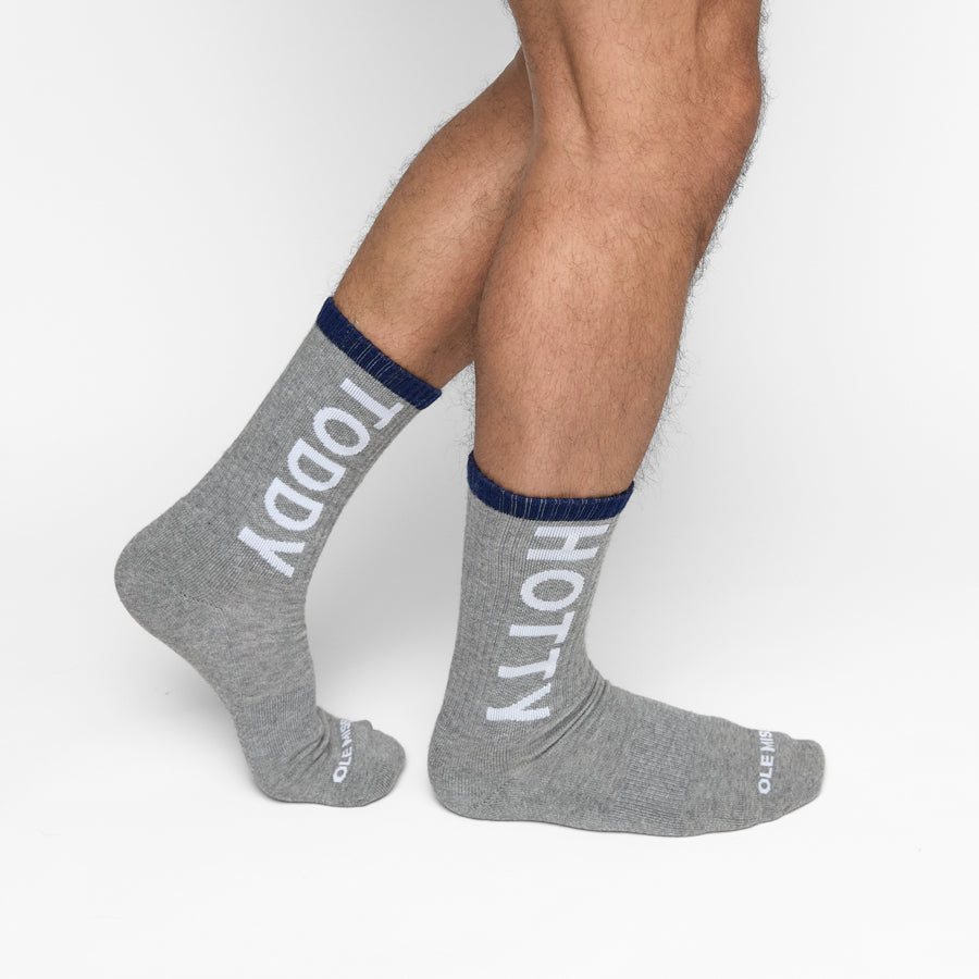 Grey athletic crew sock with white stripes and “Hotty Toddy” written vertically up the back in red, shown laid flat and worn in lifestyle images.