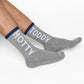 Gray socks with 'TODDY HOTTY' text worn by a person on a white background