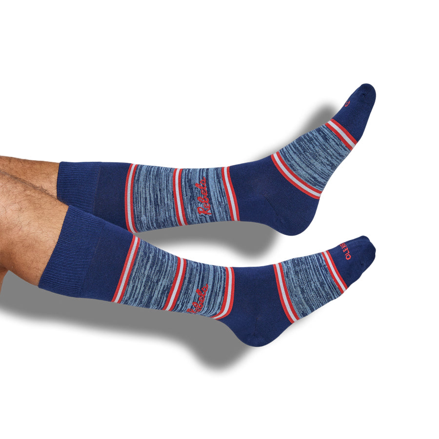 Blue socks with red and white stripes and REBELS on the ankle worn by a person on a white background