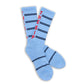 Powder blue athletic casual crew socks with double navy blue stripes and "THE SIP" written up the back of the leg laid out flat.