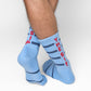 Powder blue athletic casual crew socks with double navy blue stripes and "THE SIP" written up the back of the leg on male model crossed legs.