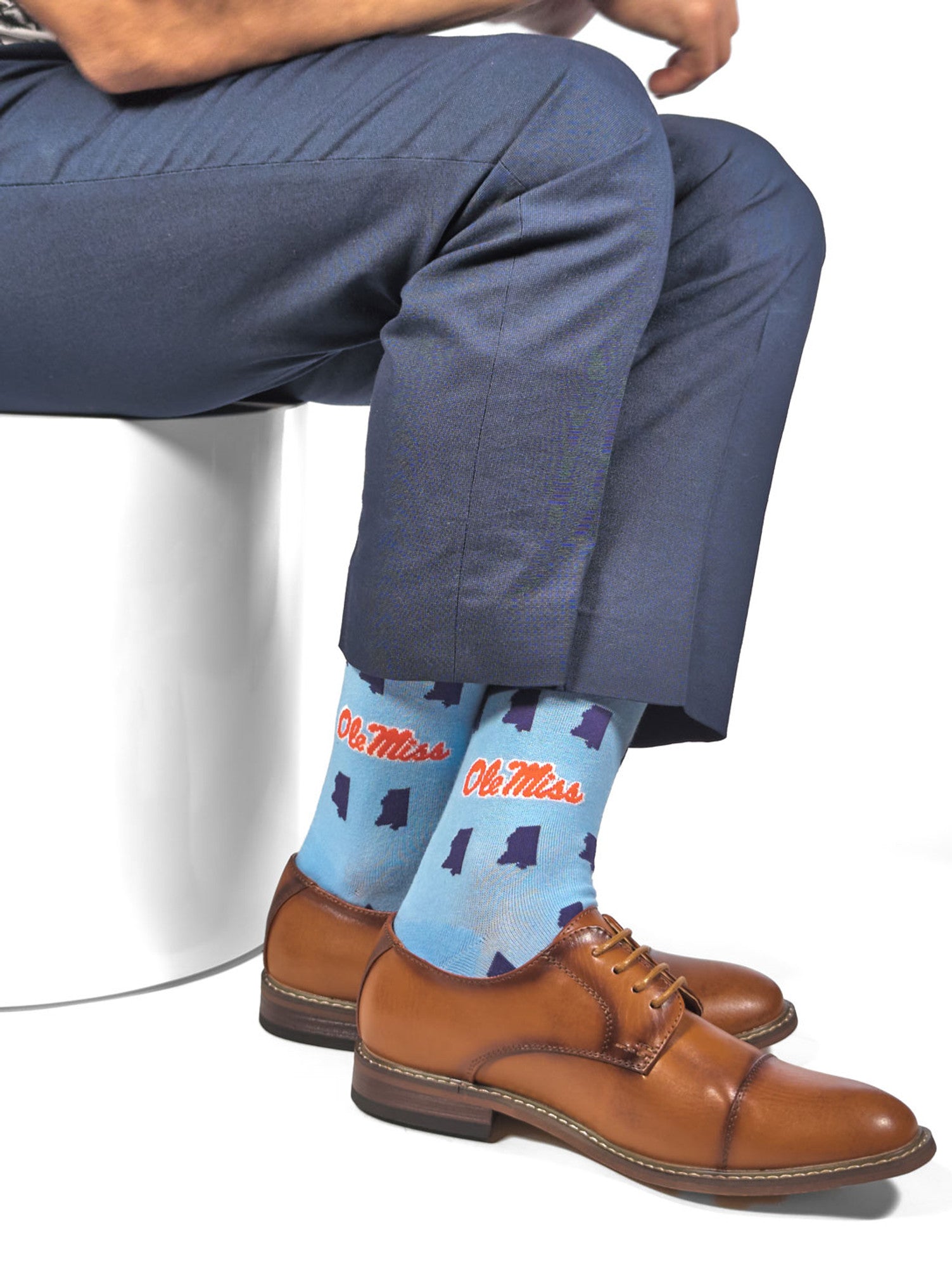 sitting in powder dress socks with Ole Miss script on the ankle and state of  Mississippi outline design