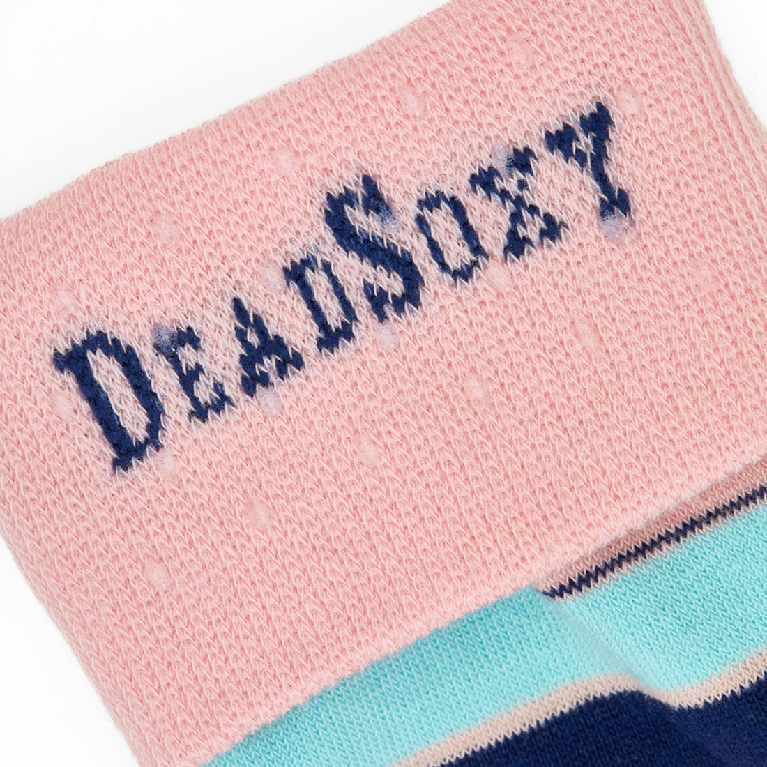 Close-up of DeadSoxy logo on blush-pink TrueStay‚Ñ¢ cuff with silicone dots on Piper supreme-cotton striped sock.