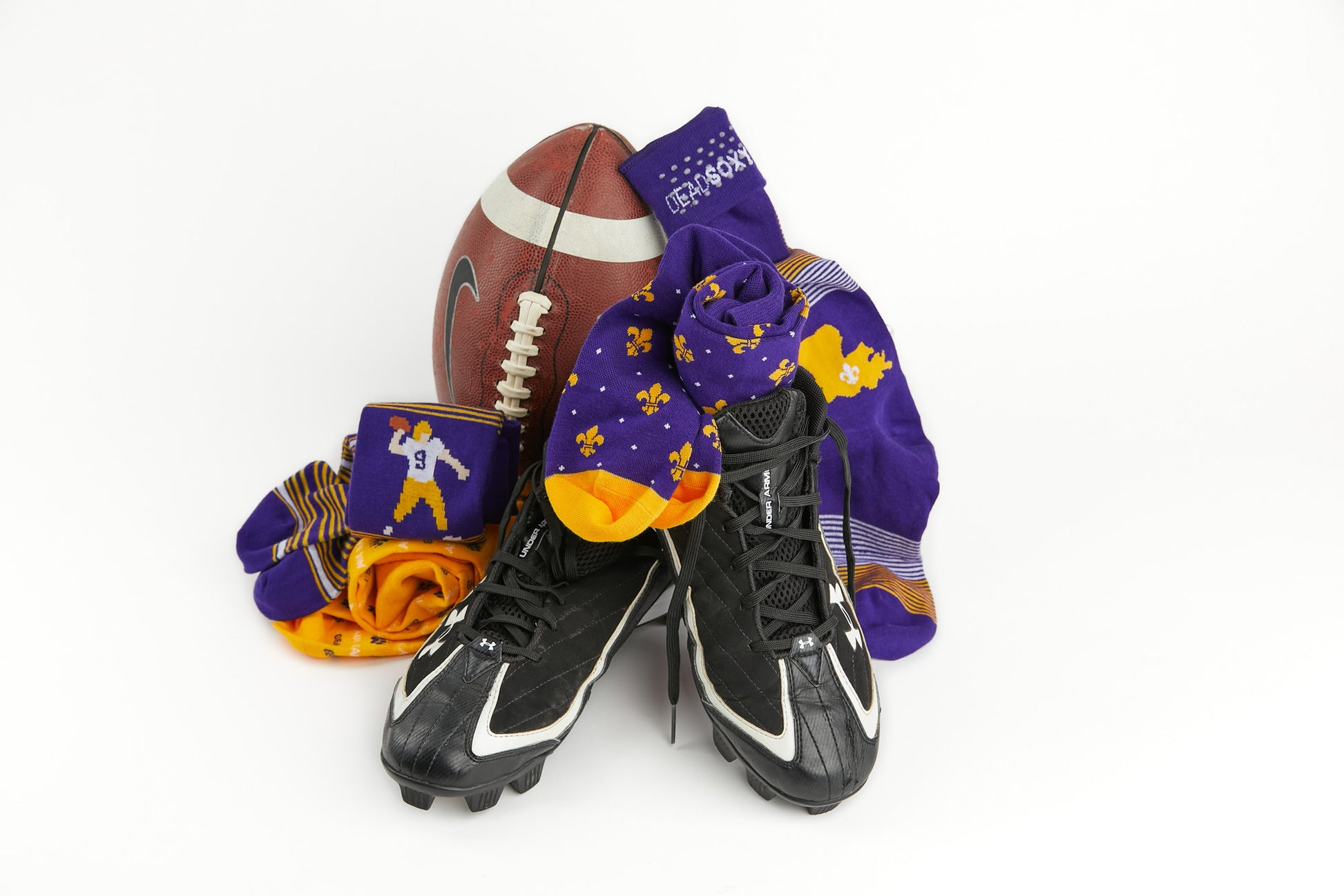 Purple and gold dress socks sitting with a football and cleats.