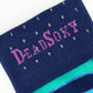 Close-up of DeadSoxy logo on navy TrueStay‚Ñ¢ cuff with silicone dots on Rolly striped sock.