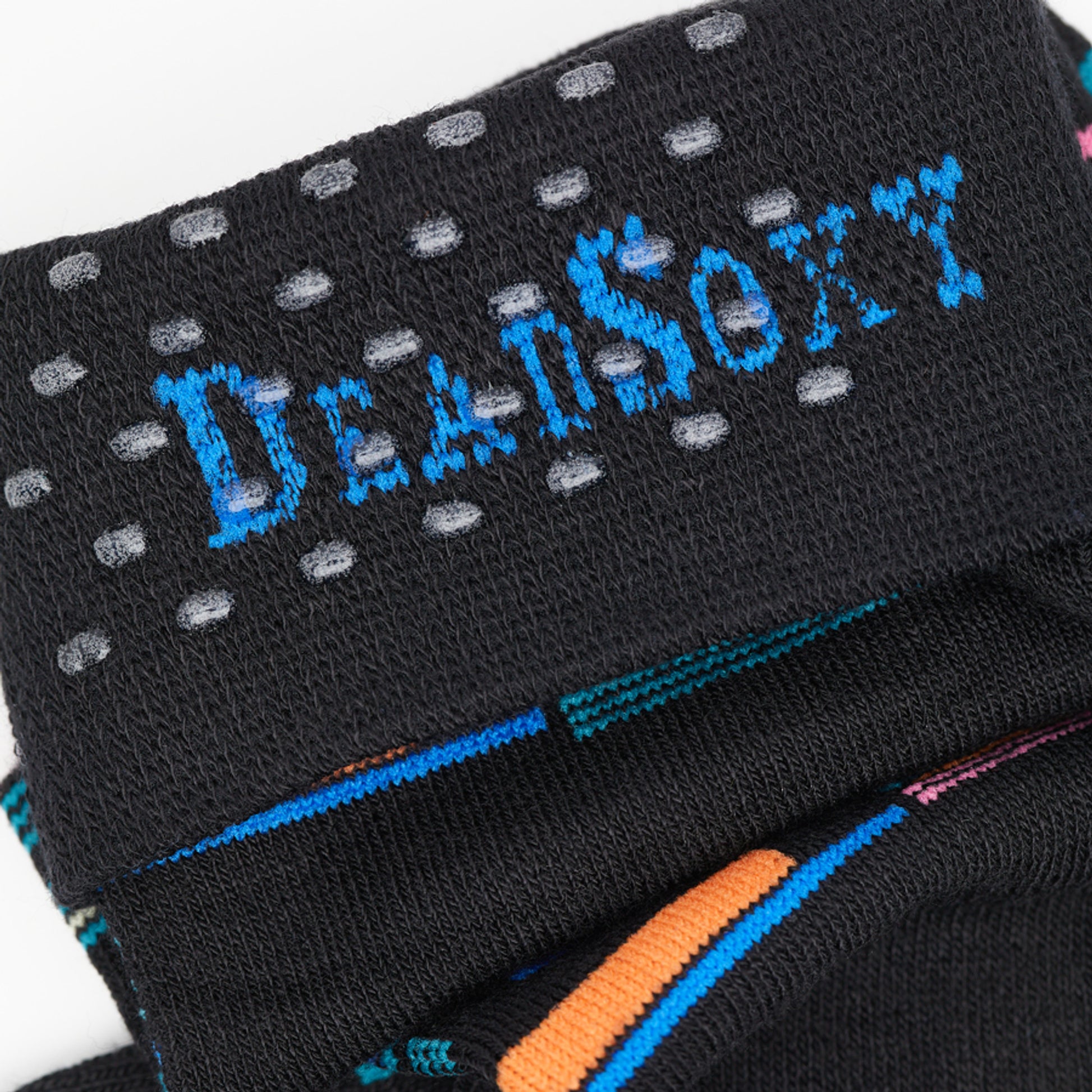 Black dress socks with green, blue, orange and grape accents in a patchwork design close up of TruseStay‚Ñ¢ in the welt.