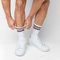 White casual crew socks with 4 thin stripes on the top in maroon and grey shown on a female model from  a distance