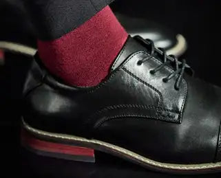 Black leather oxford shoe with a subtle red welt and contrasting tan stitching.