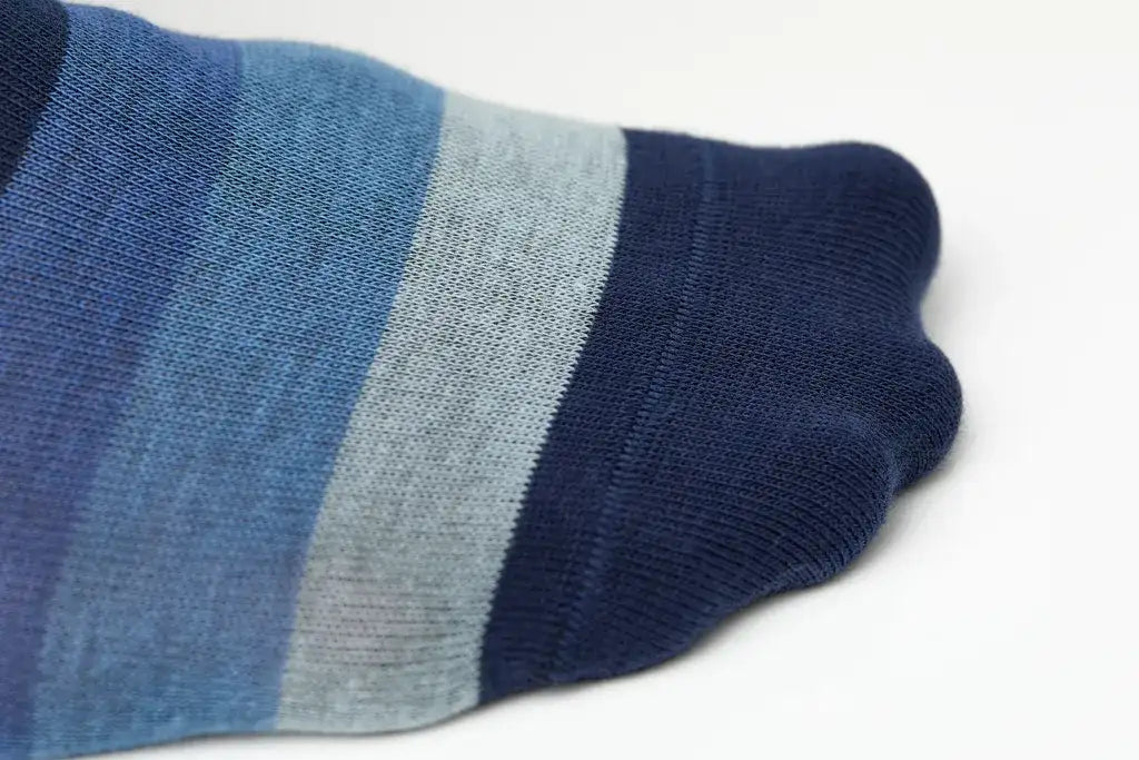 Blue striped ankle sock with a gradient of navy, medium blue, and light gray bands.