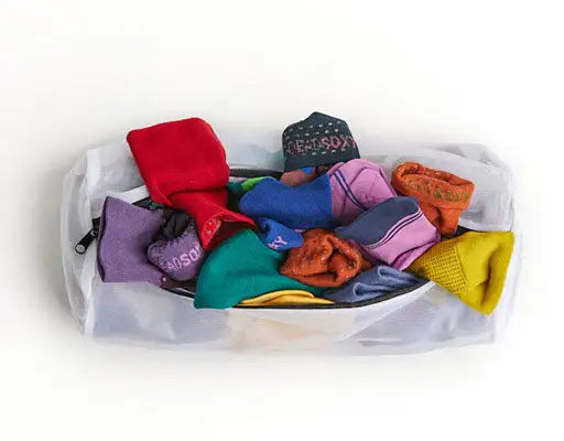 A clear mesh laundry bag filled with colorful socks.