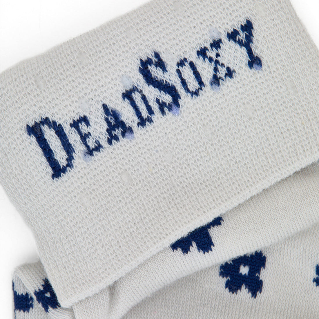 Close-up of DeadSoxy logo on light-grey TrueStay‚Ñ¢ cuff with silicone grip dots on Drew floral sock.
