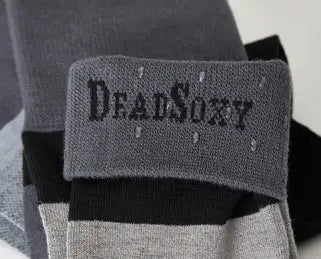 Gray and black striped socks with a ’deadsoxy’ brand label embroidered in dark gray on the cuff.